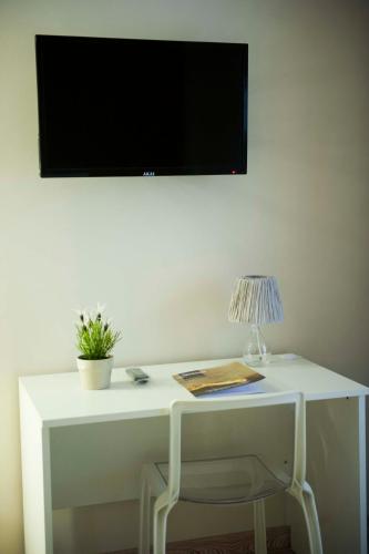 a white desk with a chair and a television on a wall at SalernoPrestige rooms in Salerno