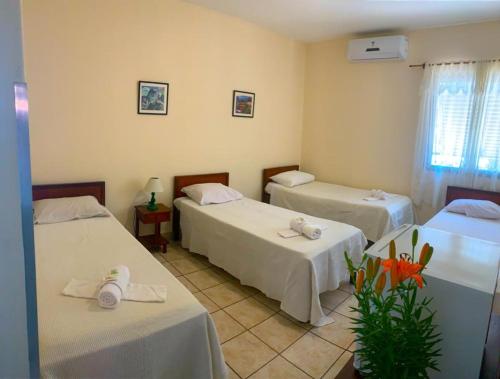 a room with two beds and two tables and a window at Hotel São Pedro in São Pedro