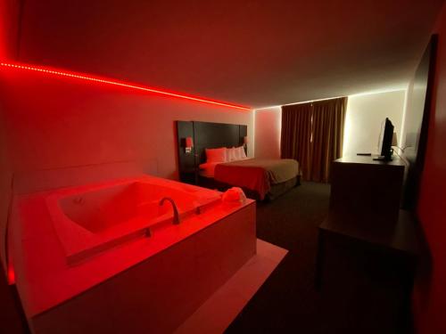 a red lighted bathroom with a tub and a bedroom at Chicago Club Inn & Suite in Oakbrook Terrace