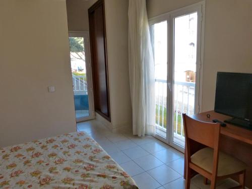 a bedroom with a desk and a television and a balcony at Hotel Tamasite in Puerto del Rosario