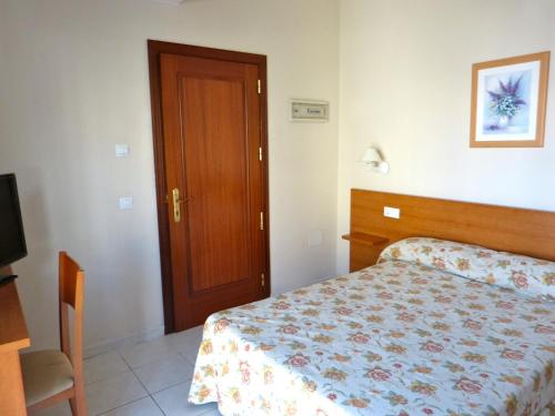 1 dormitorio con 1 cama y puerta de madera en Hotel Tamasite en Puerto del Rosario