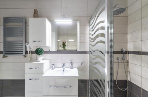 a white bathroom with a sink and a shower at Apartament na Klifowej in Mechelinki