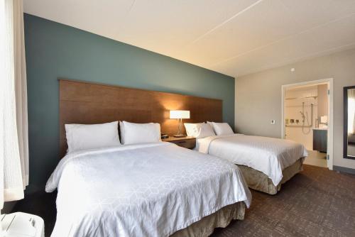 a hotel room with two beds with white sheets at Staybridge Suites - Waterloo - St. Jacobs Area in Waterloo