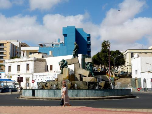 a woman walking past a statue in front of a fountain at Hotel Tamasite in Puerto del Rosario