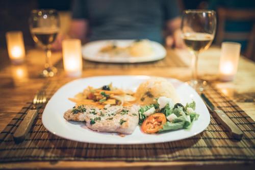 a plate of food on a table with wine glasses at Casa Strela B&B Tarrafal in Tarrafal