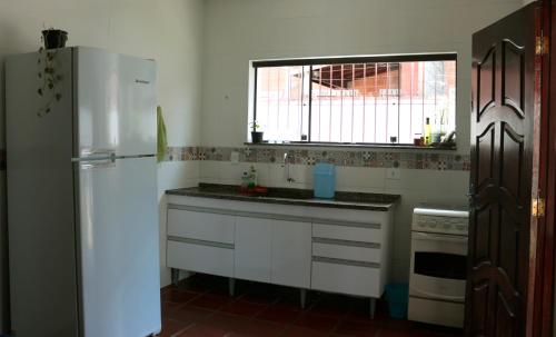 a kitchen with a white refrigerator and a window at Que onda! in Ubatuba