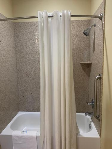 a bathroom with a white shower curtain next to a tub at Rodeway Inn & Suites in Winnfield