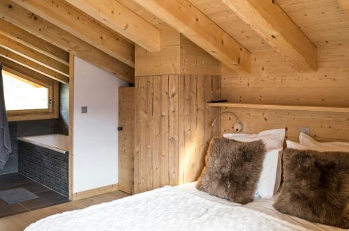 レ・コロンにあるTouti LUXURY & NEW BUILD chalet 10 pers by Alpvision Résidencesの木製の壁のベッドルーム1室、ベッド1台が備わります。
