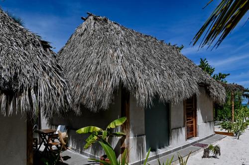 a house with a thatched roof and a table and chairs at Casa Mate BeachFront Cabañas El Cuyo in El Cuyo