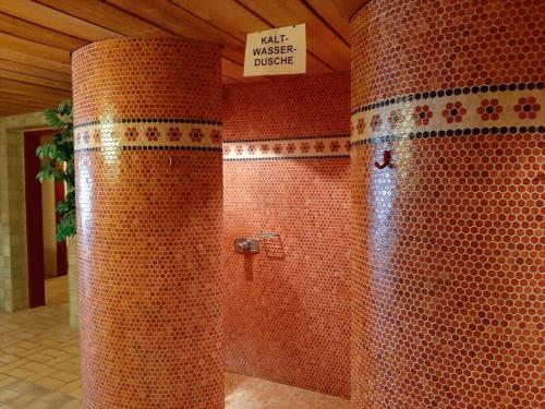 a bathroom with a shower with red tiled walls at Hotel Berghof in Sonnenalpe Nassfeld