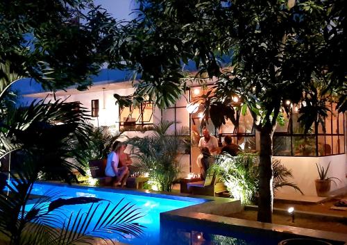 a group of people sitting around a swimming pool at night at Soiree in Zipolite