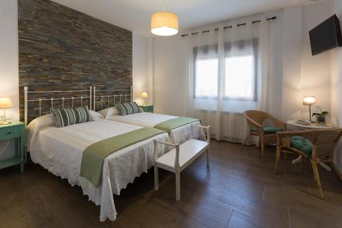 een slaapkamer met een groot bed en een bakstenen muur bij Encantos De Monfragüe in Malpartida de Plasencia