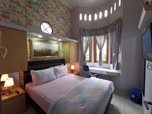 a bedroom with a large bed and two windows at Nariska Suite Homestay in Yogyakarta