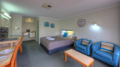 a hotel room with a bed and two chairs at Alluna Motel in Armidale