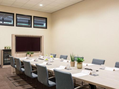 a conference room with a table and chairs and a flat screen tv at Adagio Amsterdam City South in Amstelveen
