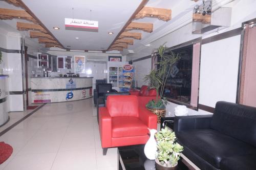 sala de estar con sillas rojas y sofá en مون تري للشقق المخدومة فرع الرياض, en Riad