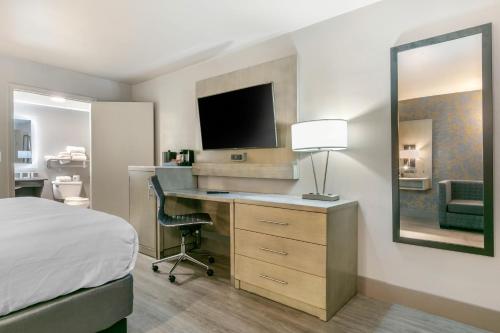 a hotel room with a bed and a desk with a television at Clarion Inn Murfreesboro Old Fort Pkwy in Murfreesboro
