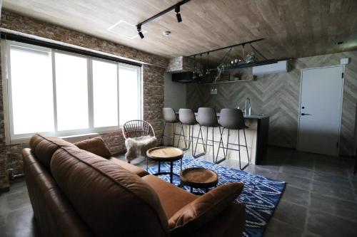 Hotel MAISON SAPPORO في سابورو: غرفة معيشة مع أريكة بنية ومطبخ