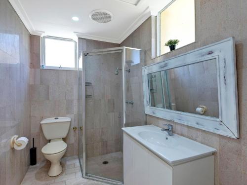 a bathroom with a shower and a toilet and a sink at Golden Sands 1 - Absolute Beachfront in Blue Bay 