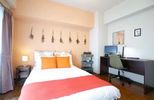 a bedroom with a bed and a desk and a computer at Wings Hakata in Fukuoka