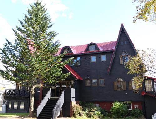 a black house with a tree in front of it at Pension Fullnote in Kutchan