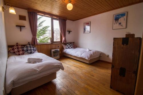 a bedroom with two beds and a window at Pension Fullnote in Niseko