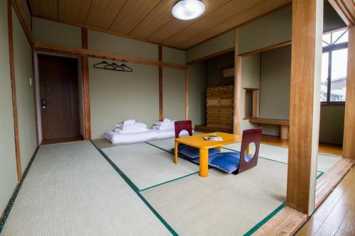 um quarto com uma mesa e cadeiras e uma cama em Pension Fullnote em Niseko