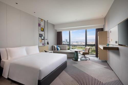 Cette chambre comprend un grand lit blanc et une table. dans l'établissement Crowne Plaza Foshan Nanhai - an IHG Hotel, à Canton
