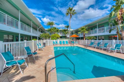 einen Pool in einem Resort mit blauen Stühlen und Palmen in der Unterkunft Tropic Terrace #40 - Beachfront Rental condo in St Pete Beach