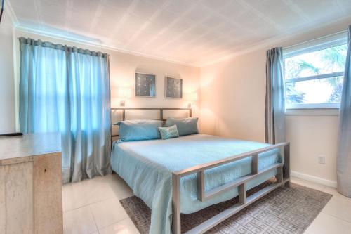 Schlafzimmer mit einem Bett mit blauer Bettwäsche und einem Fenster in der Unterkunft Tropic Terrace #40 - Beachfront Rental condo in St Pete Beach