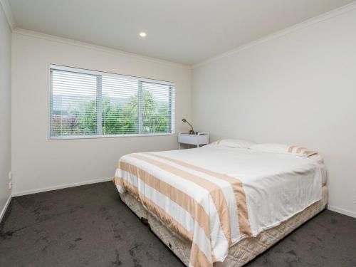 a white bedroom with a bed and a window at Millies Place - Mangawhai Holiday Home in Mangawhai