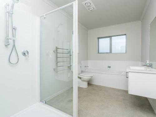 ein weißes Bad mit einer Dusche und einem WC in der Unterkunft Millies Place - Mangawhai Holiday Home in Mangawhai