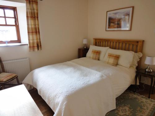 a bedroom with a white bed and a window at The Courtyard in Errol