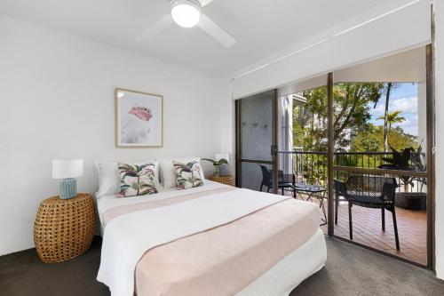 a white bedroom with a large bed and a balcony at Naousa II Apartment 5, Little Cove in Noosa Heads