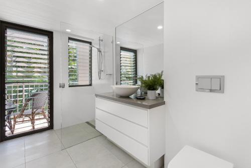 a white bathroom with a sink and a mirror at Naousa II Apartment 5, Little Cove in Noosa Heads