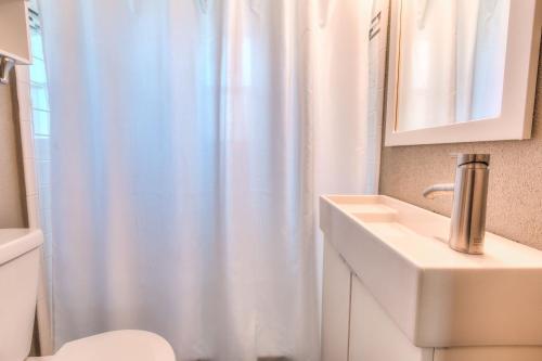 ein Badezimmer mit einem weißen Duschvorhang und einem Waschbecken in der Unterkunft Tropic Terrace #55 - Beachfront Rental condo in St Pete Beach
