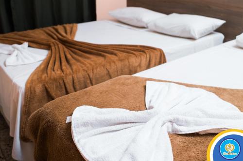 two beds with brown and white towels on them at Don Charleaux Hotel in Aparecida