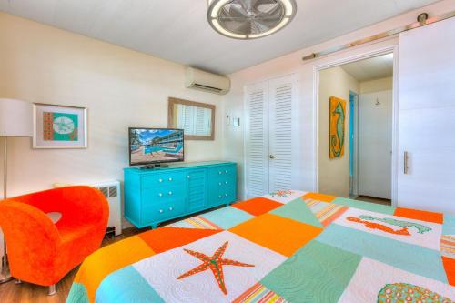 sypialnia z kolorowym łóżkiem i pomarańczowym krzesłem w obiekcie Tropic Terrace #29 - Beachfront Rental apts w St Pete Beach