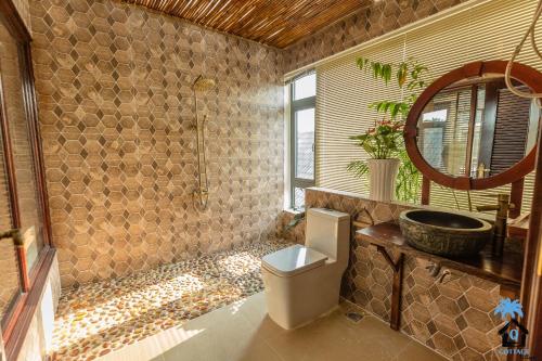 a bathroom with a toilet and a sink and a mirror at Cottage Village in Phu Quoc