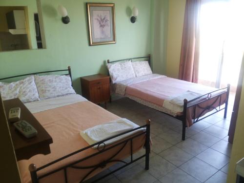 a bedroom with two beds and a table at Hotel Ifigenia Paralia Katerinis plaz in Paralia Katerinis