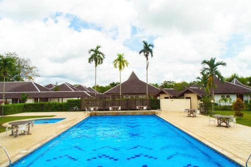 uma piscina em frente a uma casa com palmeiras em Rungan Sari Meeting Center & Resort em Guhung
