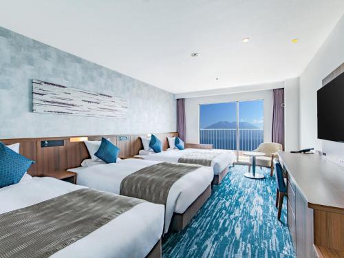 a hotel room with three beds and a flat screen tv at Art Hotel Kagoshima in Kagoshima