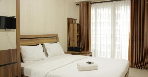 a bedroom with a large white bed and a window at Spacious Studio Room at Gateway Pasteur Apartment near Exit Toll Pasteur By Travelio in Bandung