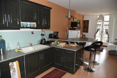 - une cuisine avec des placards noirs, un évier et une table dans l'établissement Pied à terre au bord de mer, à Sète