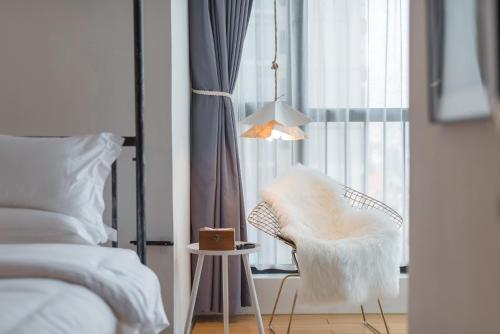a bedroom with a white chair next to a window at Su Jiu Apartment in Nanning