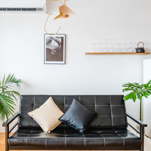 a black leather couch with pillows in a living room at Su Jiu Apartment in Nanning