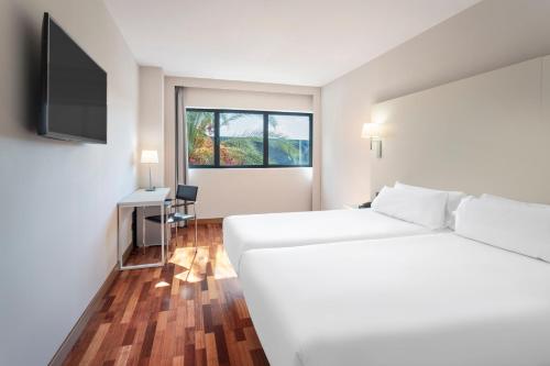 a white room with a bed and a television at B&B HOTEL Jerez in Jerez de la Frontera