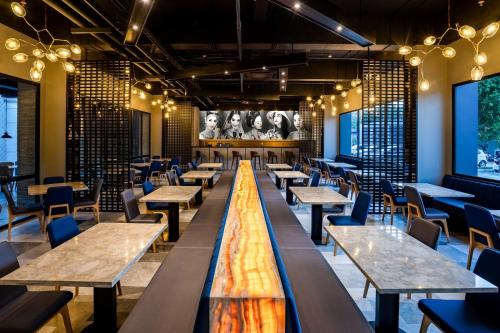 チレゴンにあるAston Cilegon Boutique Hotelのテーブルと椅子、大画面のレストランを併設しています。