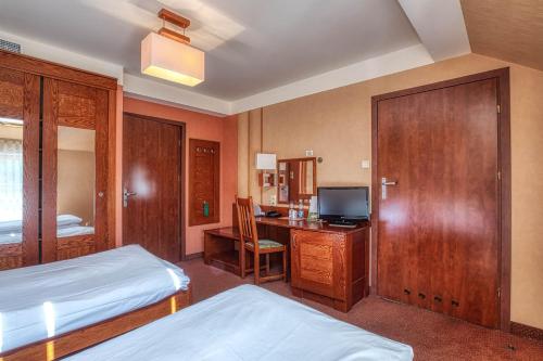 a bedroom with a bed and a desk with a computer at Dom Oliwski in Gdańsk