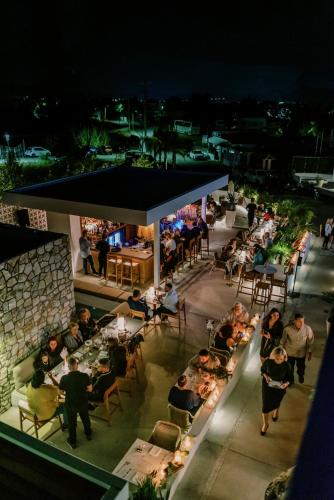 a group of people sitting at tables on a patio at night at Kouros Exclusive Hotel & Suites - Adults Only in Faliraki